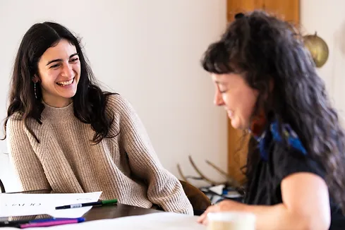 Two people sitting at a table, facing each other and laughing.